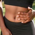 Donna che stringe l'addome per dolore e colon irritabile  Consulenza con il nutrizionista a Catania