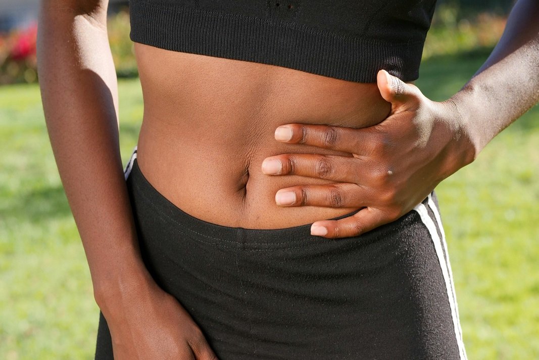Donna che stringe l'addome per dolore e colon irritabile Consulenza con il nutrizionista a Catania